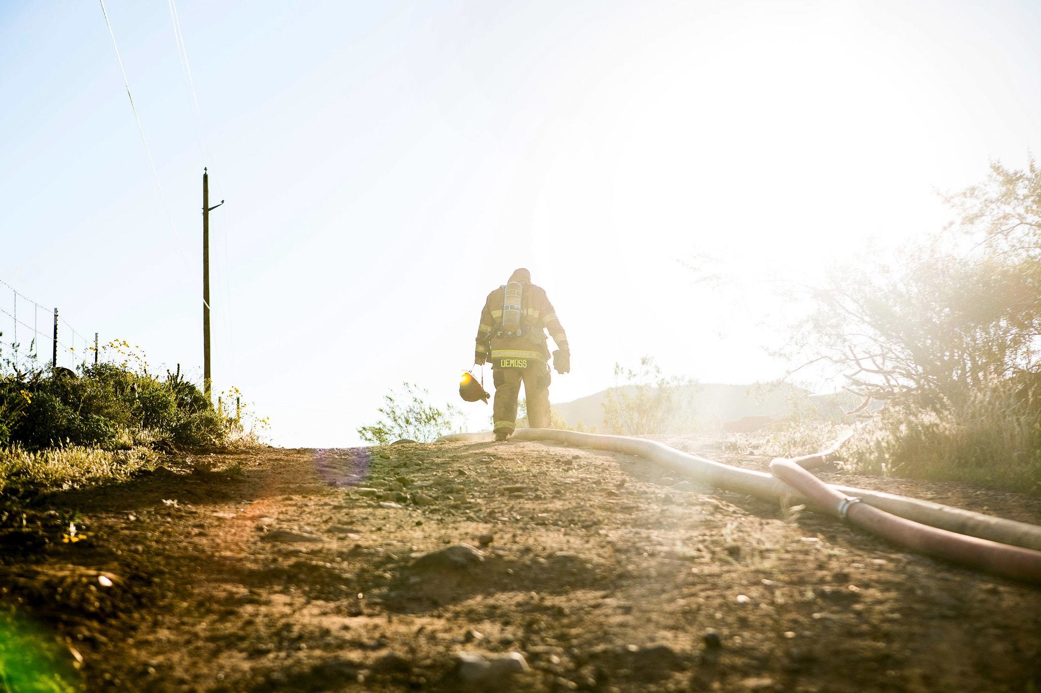 A Rural/Metro firefighter walks from the remains of a fire in Cave Creek, Ariz. The company sues to collect some bills from fire customers.